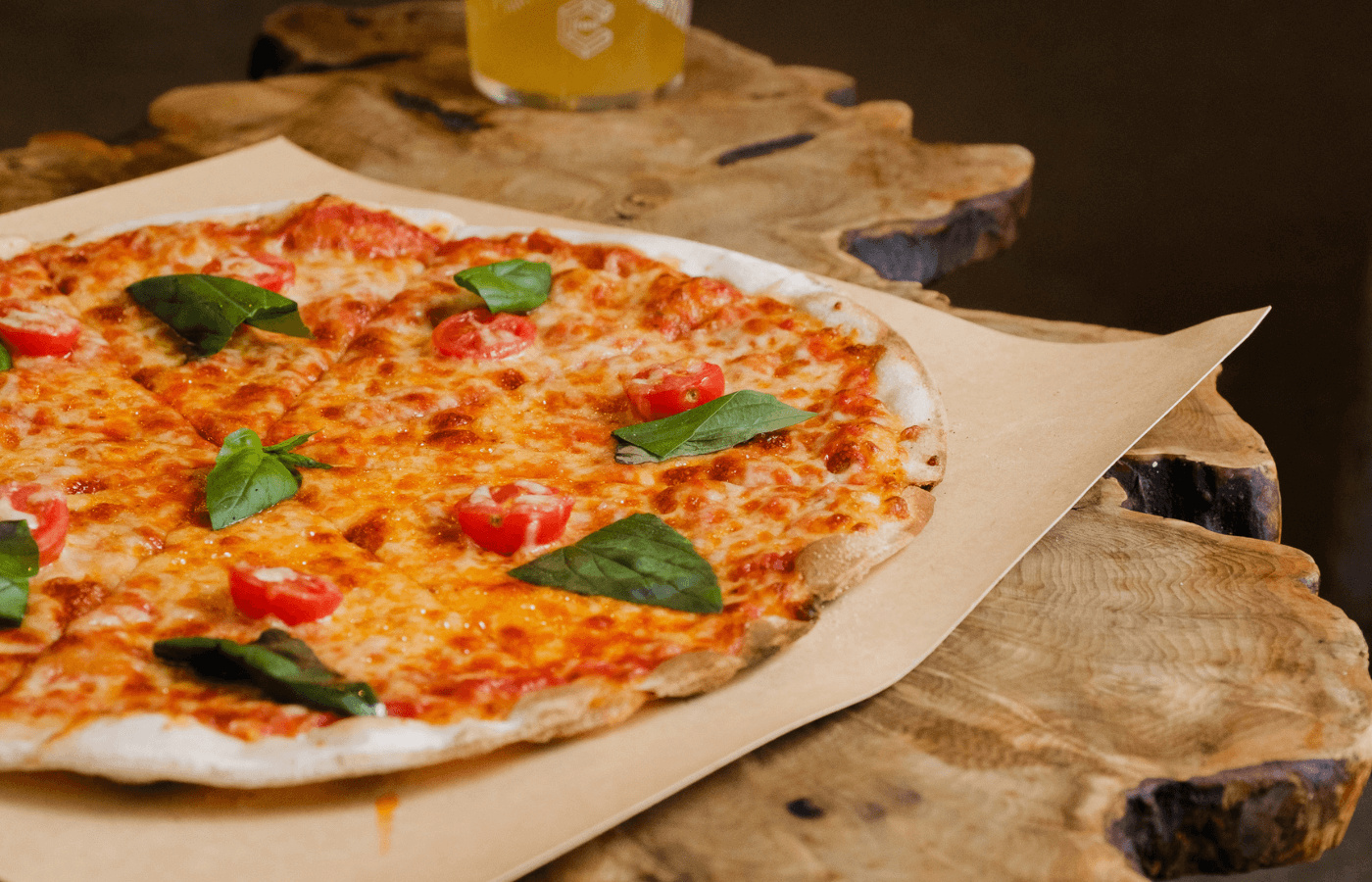 Margarita pizza on a wooden board with a glass of beer in the background